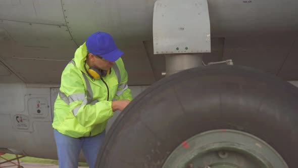 Man Specialist Performs a Technical Check of the Chassis of a Passenger Aircraft at the Airport