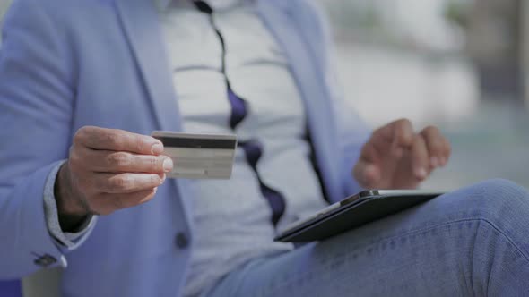 Cropped Shot of Man with Credit Card Using Tablet Pc