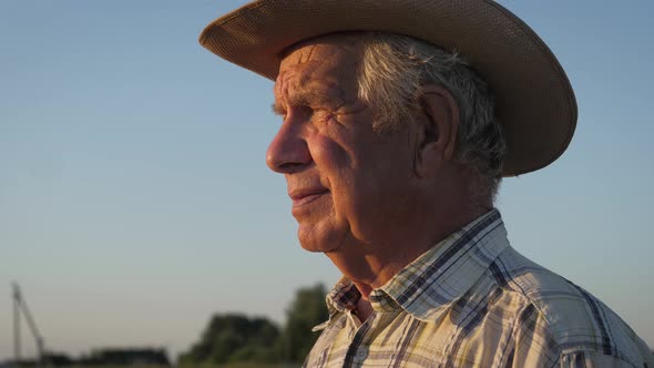 Portrait Of Old Caucasian Man With Hat On Outdoor Turns His Head Towards Sunset