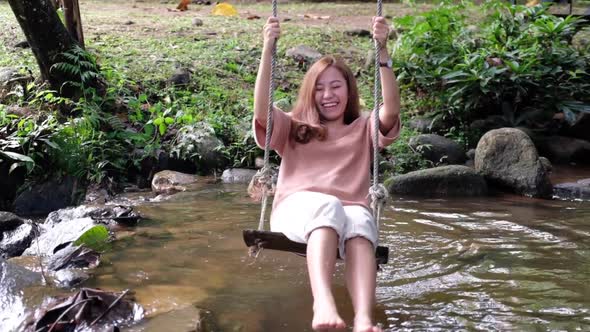 Slow motion of a woman playing with wooden swing in the waterfall