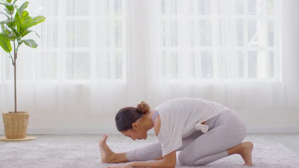 Calm of wellness Asian young woman sit on bed breathing and stretching before do yoga