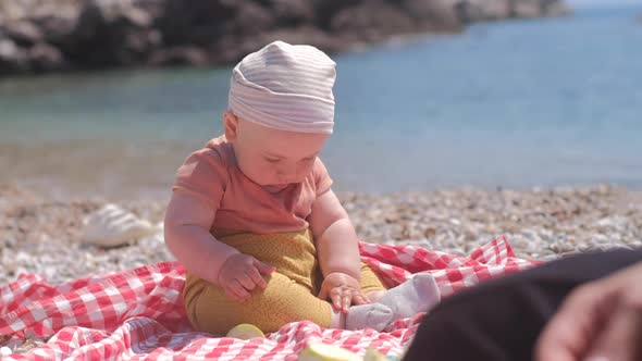 Baby boy 6 months eating an apple on the background of the sea on a sunny day