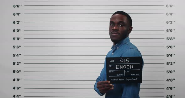 Mugshot of Afro American Guy Turning to Sides While Holding Sign and Posing for Photo 