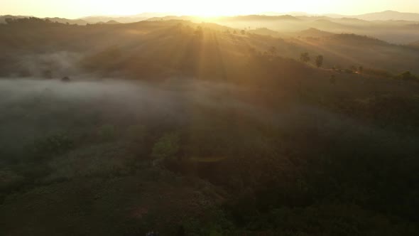 4K aerial view over a misty mountainous area. The great golden sun in the morning