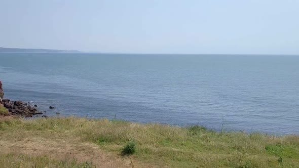 STATIC CROP, Aerial Pull Back over a grassy ocean bluff along the Jurassic Coast cliffs