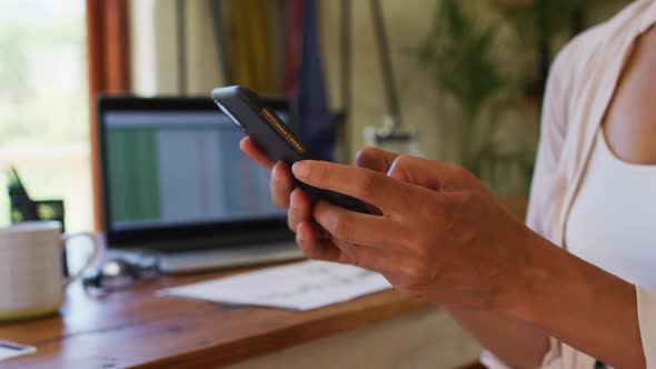 Mid section of woman using smartphone while working from home