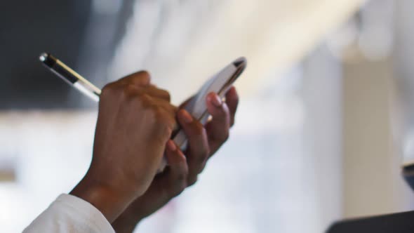 Mixed race man giving african american female cafe worker his smartwatch in order to pay