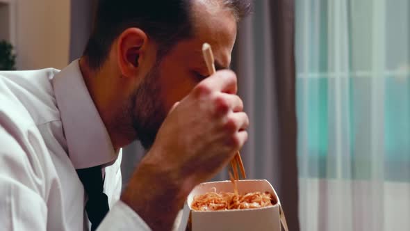 Close Up of Businessman with Tie Eating Noodles From a Box