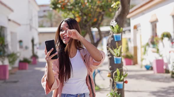 Joyful Ethnic Woman Using Smartphone While Walking