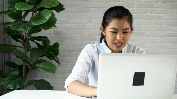 Happy Friendly Asian Woman Using a Laptop and Talking Making Video Call Conference at Home