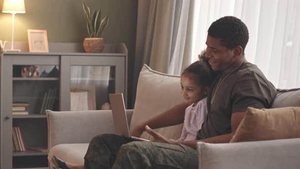 Military Man and Little Girl Waving at Camera Having Video Call alt