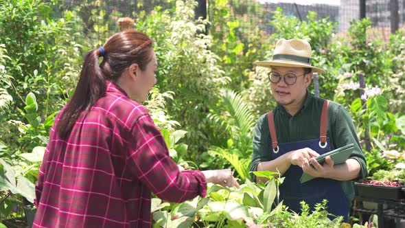 4K Asian man plant shop owner helping woman customer choosing potted plants in store