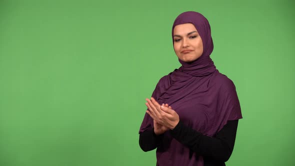 A Young Beautiful Muslim Woman Applauds to the Camera with a Smile  Green Screen Background