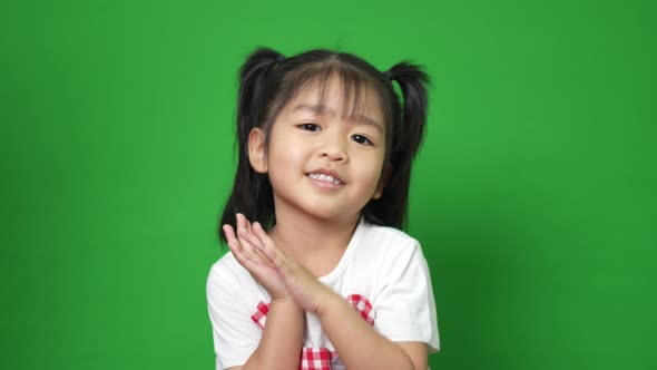 Portrait of happy and funny Asian child girl on green screen background, a child looking at camera.