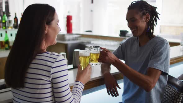 Diverse group of happy friends drinking beers and talking at a bar