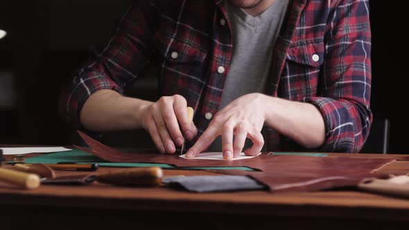 Man Tailor Cutting Artificial Leather with Ruler Closeup