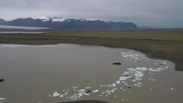 Glacier in Iceland with blue ice floating in water and mountain view with drone video moving forward