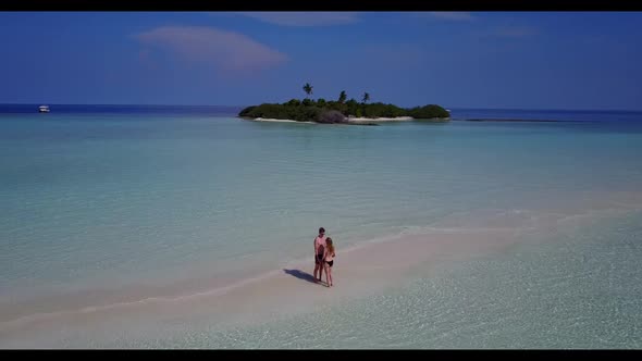 Two lovers sunbathe on marine seashore beach voyage by transparent water with white sand background 