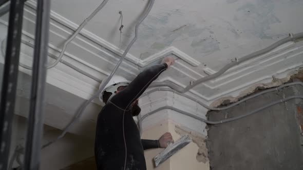 Fat Bearded Adult Man in Protective Helmet and Black Tight Fitting Clothing Remove Construction