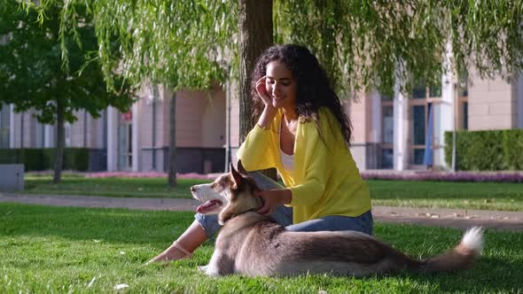 Rest in Park with Dog Young Woman and Her Pet are Sitting on Green Grass