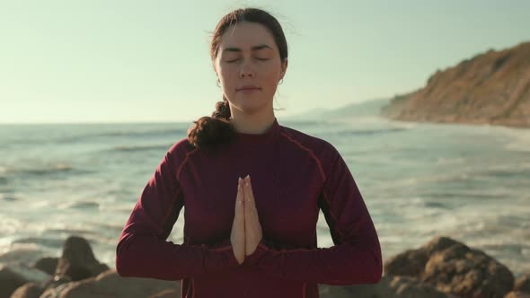 Smiling woman meditates with her palms folded in a namaste gesture and and breathing deeply