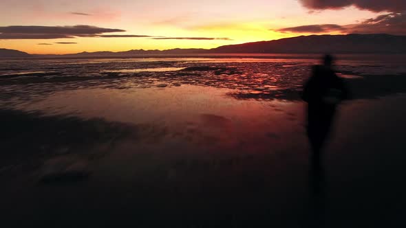 Flying past man walking on ice during colorful sunset