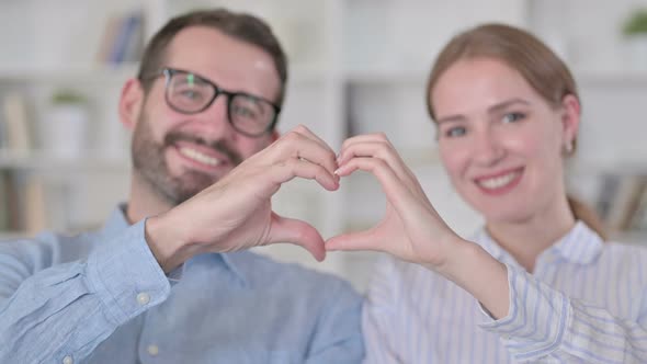 Portrait of Happy Young Couple Showing Heart Sign with Hands