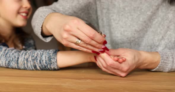 Mother helping to cut her girls daughter fingernails by clipper at home