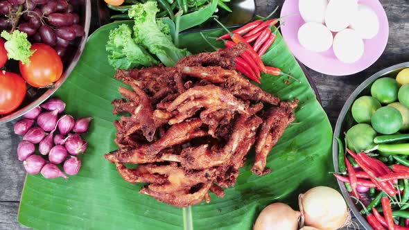 Top down view Fried chicken feet displayed on banana leaf, table full of Vegetables