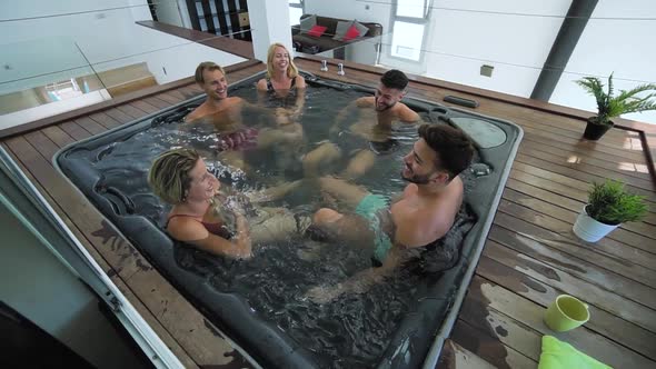 Happy friends enjoying vacations in jacuzzi luxury house