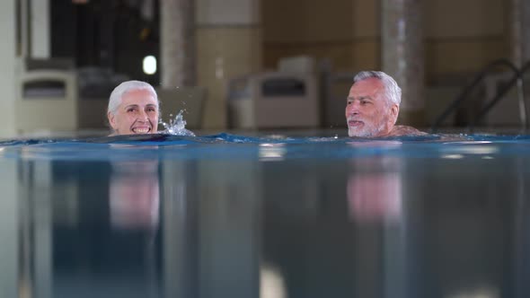 Active Mature Couple Swimming in Pool of Spa Hotel