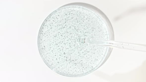 Transparent Cosmetic Gel Fluid Dripping From Pipette Into the Glass Bowl of Petri