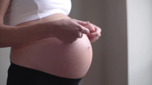 Close-up of pregnant woman caressing her bare stomach