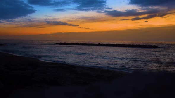 Gorgeous Orange Sunset on Mediterranean Sea. Dark Waves of Calm Ocean Water Crashing on the Beach