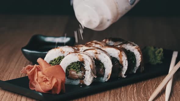 Sprinkle Sushi with Sesame Seeds on a Wooden Table in Restaurant