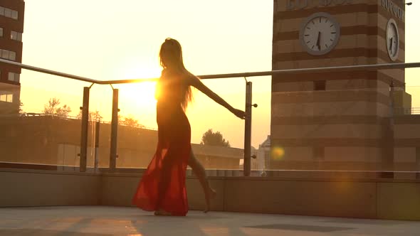 Beautiful Young Girl Dancing on the Street of a Modern City in the Sunset Light