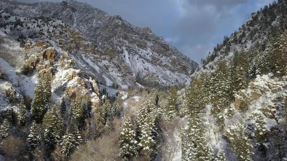 Slowly flying through snow covered canyon as the sun shines on the cliffs