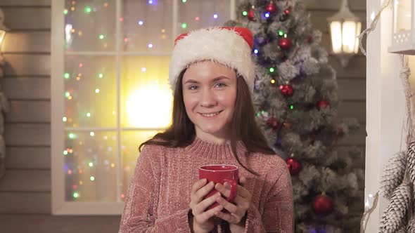 Pretty Woman in Red Hat with Cup of Tea Smiling and Looking at Camera. Close-up