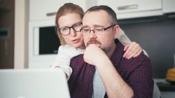 A Serious Couple Talking While Looking at a Laptop Screen