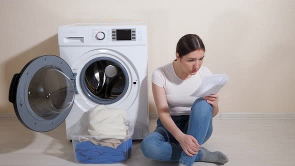 Young Housewife in Jeans Learns Settings of New Washing Machine with Instruction