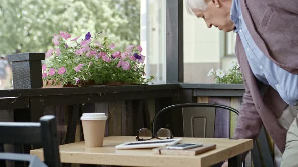 Elderly Businessman Reading from Digital Tablet in Cafe