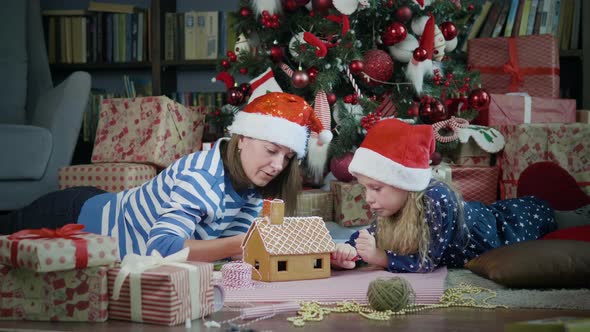 Mother with daughter decorates gingerbread house