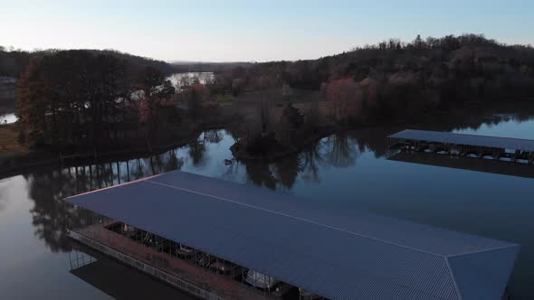 Drone footage slowly rising above the boat docks with calm water and land behind it