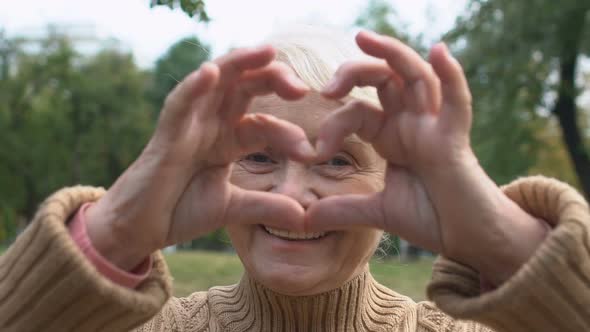 Happy Woman in Her 70 Showing Heart Sign With Hands, Symbol of Love, Close-Up