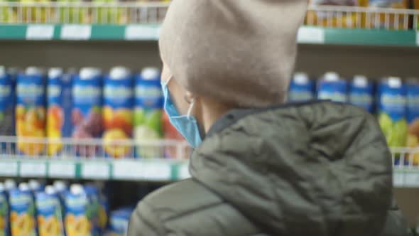 Woman in Medical Mask Chooses Juice