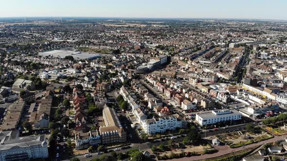 Reverse aerial view of Clacton-on-Sea promenade and parks on a sunny day