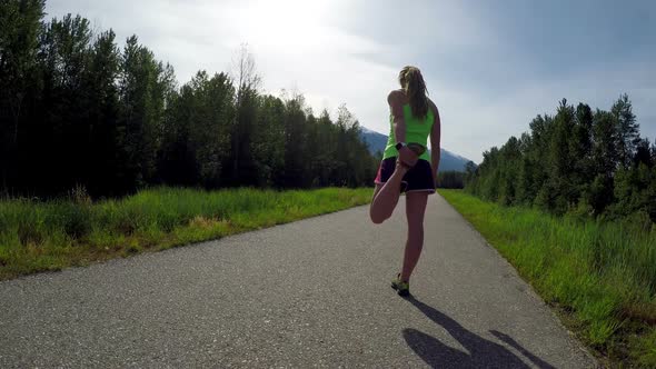 Fit woman doing stretching exercise in road 4k