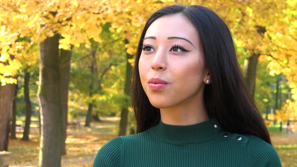 A Young Asian Woman Looks Around a Park on A Sunny Day