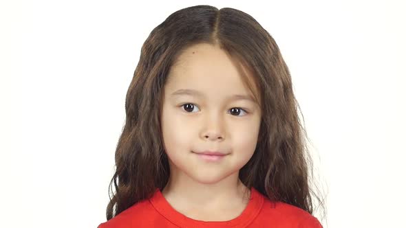 Close-up Little Dark-haired Kid Smiling on White Background. Slow Motion