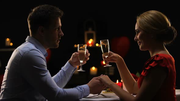 Sweet Passionate Couple on Romantic Date Drinking Champagne and Clinking Glasses